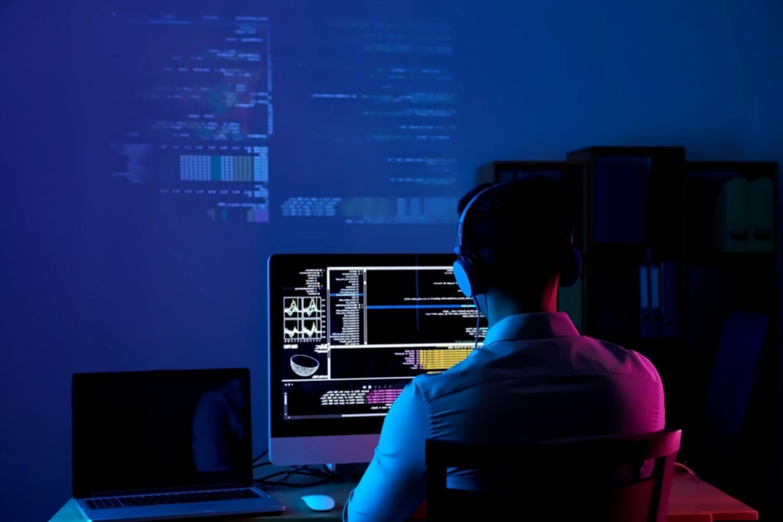 Estudiantes trabajando en optimización de juegos 3D con múltiples monitores mostrando código y gráficos de rendimiento